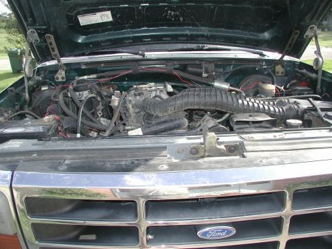 1993 Ford Bronco - The engine bay of a green 1993 Ford Bronco is open, revealing the engine and front grille.