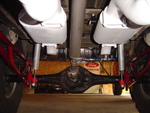1978 Ford Bronco - Underside view of a vehicle's rear axle and exhaust system with custom red suspension parts.