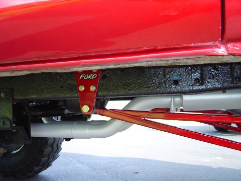 1978 Ford Bronco - Close-up view of the frame and suspension components on a red 1978 Ford Bronco, showing a "FORD" branded bracket.