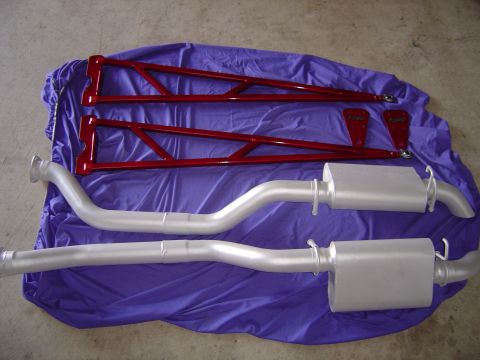 1978 Ford Bronco - Custom red traction bars and dual exhaust mufflers are displayed on a purple tarp.