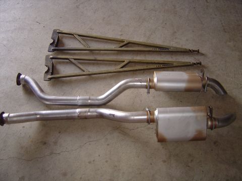 1978 Ford Bronco - Exhaust system components and braces are laid out on a concrete surface.
