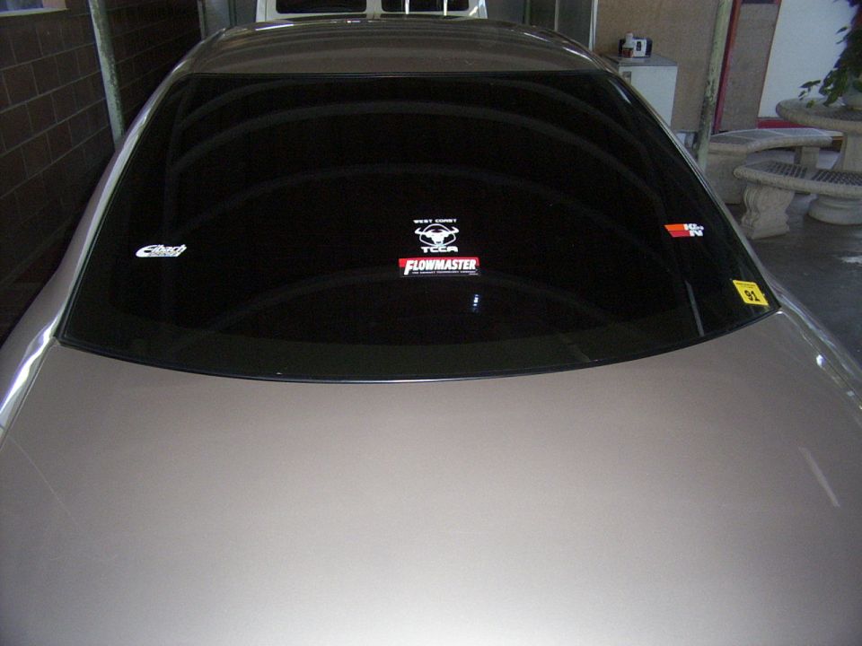 Rear window of a car with Flowmaster, K&N, and other stickers. "SUPERMOTORS.NET" watermark at bottom right