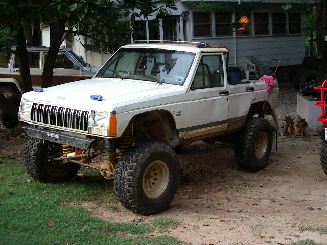 White Jeep Comanche pickup, 3q-front view, lifted with off-road tires
