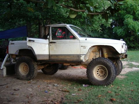 1985 Ford Bronco - This modified Jeep Comanche pickup truck features a lifted suspension and oversized tires, suggesting it's built for off-road use.