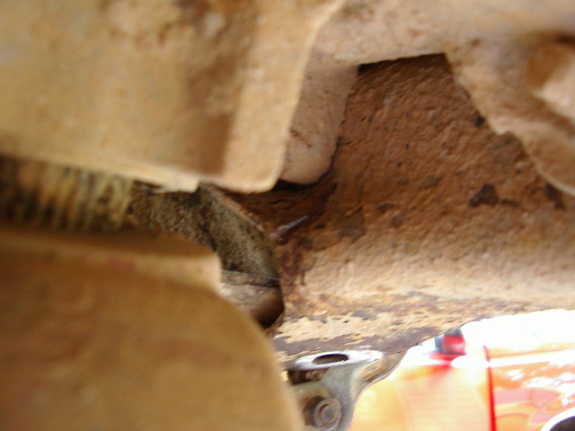 Close-up of rusty mud-caked truck underbody frame and corroded bracket