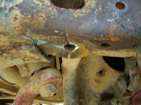 1985 Ford Bronco - Close-up of a severely corroded vehicle frame section, showing a crack and evidence of repair work.