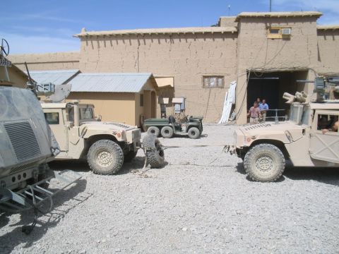 1981 Ford Bronco - Several military vehicles, including Humvees and a six-wheeled utility vehicle, are present in a desert compound.