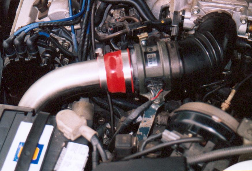Engine bay with polished intake pipe, red coupler, and blue spark plug wires
