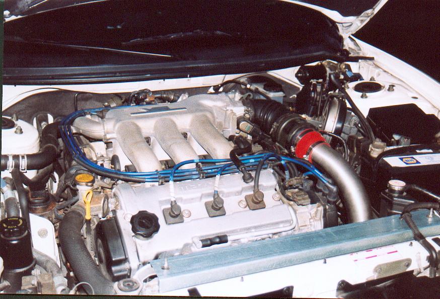 Mazda V6 engine bay with blue plug wires and red intake coupler