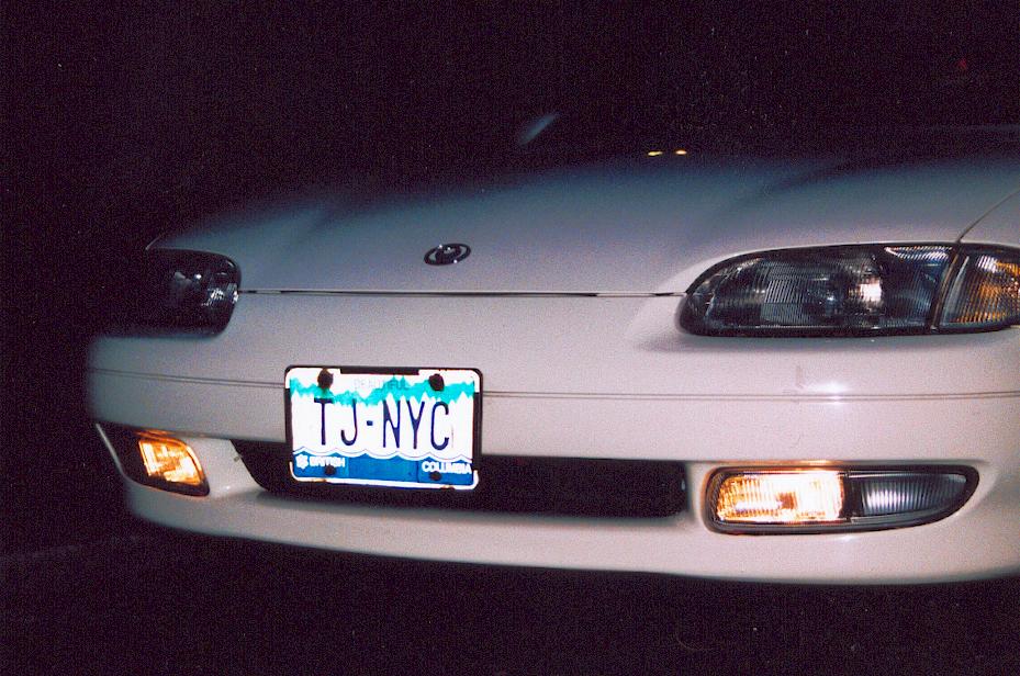 Front of white Mazda coupe at night with fog lights on and BC plate TJ-NYC