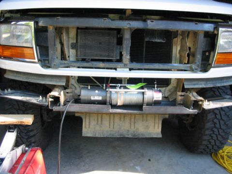 1995 Ford Bronco - A winch is mounted to the front bumper of a truck, obscuring the grille and radiator.
