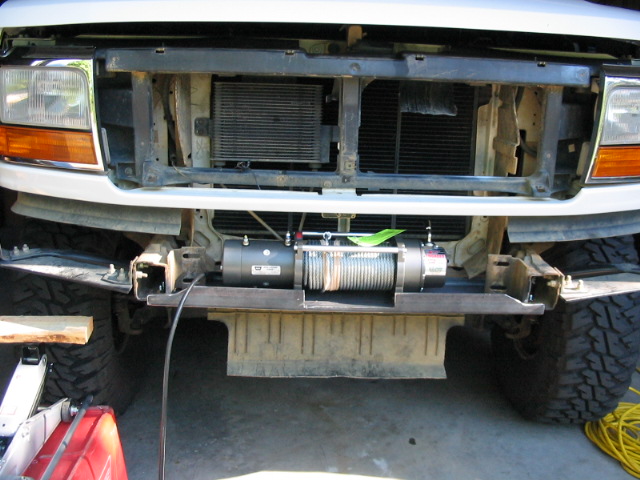 White Ford Bronco front end with electric winch mounted on bumper crossbar, grille removed