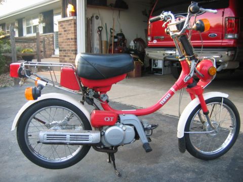 1985 Ford LTD Crown Victoria - A red Yamaha moped is parked in front of an open garage door with a red Ford van behind it.