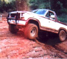 1981 Ford Bronco - This 1981 Ford Bronco is navigating a muddy, off-road trail with a clear blue sky above.