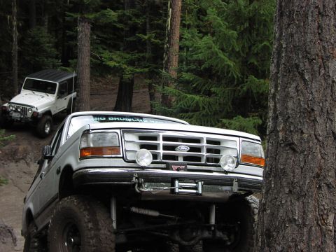 1995 Ford Bronco - A lifted white Ford Bronco navigates an off-road trail with another Jeep in the background.