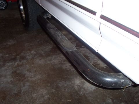 1994 Ford Bronco - Side view of a white 1994 Ford Bronco, focusing on the black side step slider.
