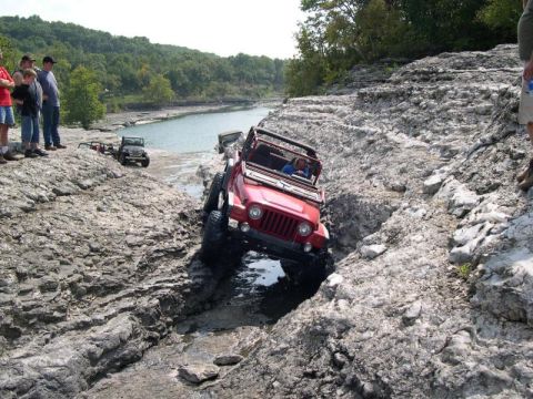 1999 Jeep TJ - Jeep TJ tackling a challenging rocky obstacle course near a body of water.