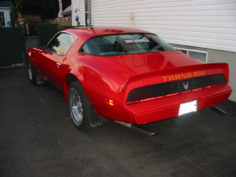 1985 Ford Bronco - Rear view of a red 1977 Pontiac Trans Am with aftermarket exhaust pipes.
