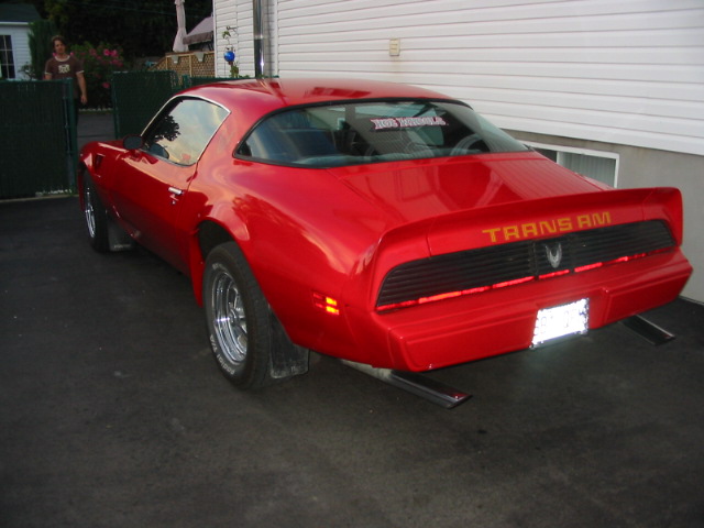 Red 1977 Pontiac Trans Am parked on asphalt, rear view showing Trans Am badging and spoiler