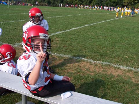 1994 Ford Bronco - A young football player sits on the bench, signaling for quiet during a game.