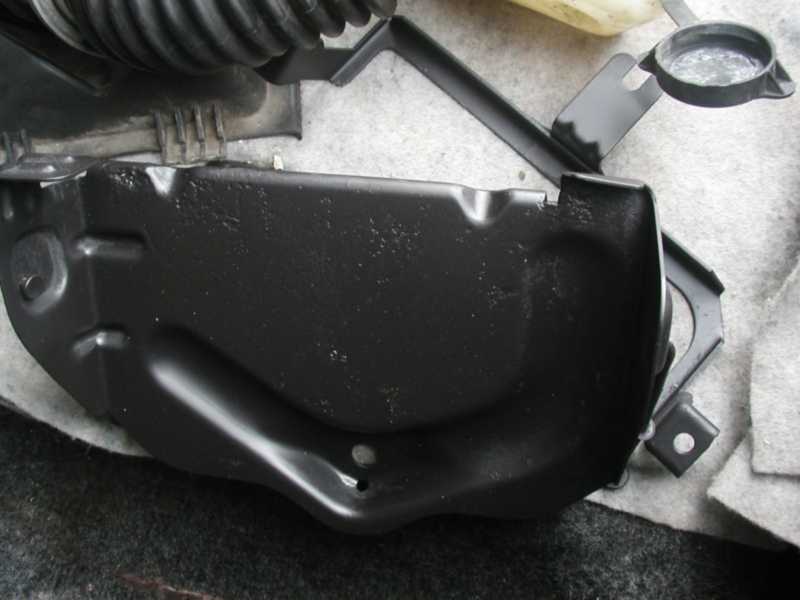 Black painted metal engine bay component with mounting bracket attached