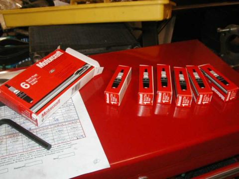 1993 Ford Taurus - Motorcraft spark plugs are laid out on a red surface next to a service document.