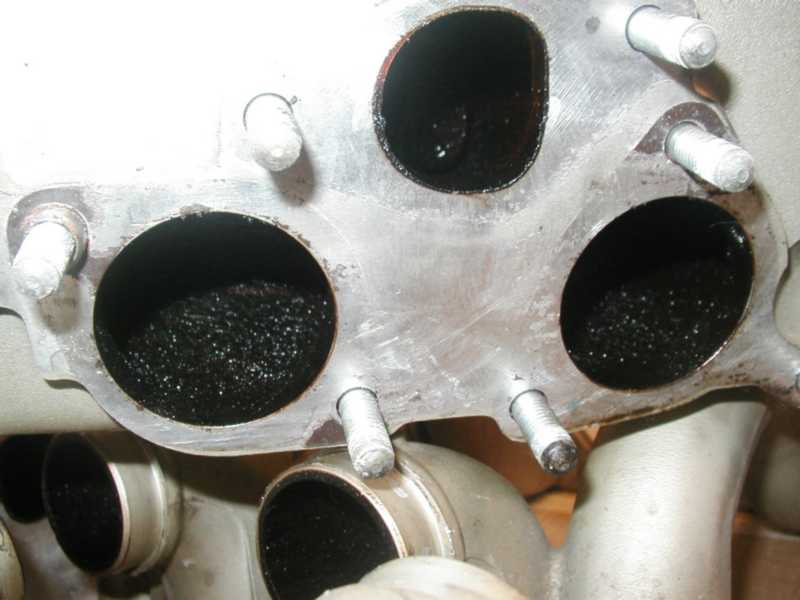Close-up of exhaust manifold ports filled with carbon buildup