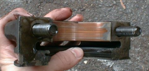 1990 Ford Bronco - Close-up of a worn engine bearing part being held.