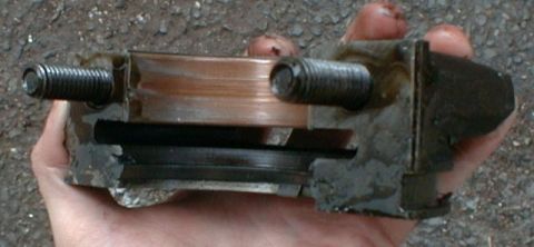 1990 Ford Bronco - A close-up view of a greasy engine part held in a person's hand.