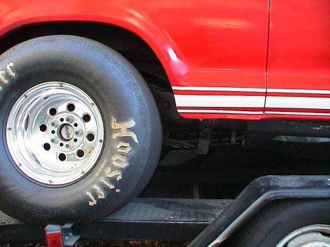 1979 Ford Bronco - Side view of a red 1979 Ford Bronco a Hoosier drag tire and white side stripe.