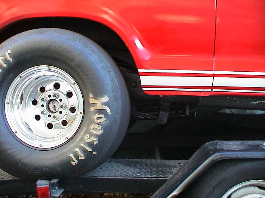 Red truck on trailer with Hoosier tire on polished aluminum drag wheel, white pinstripe