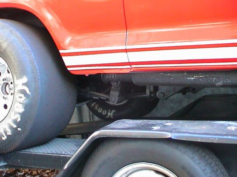 1979 Ford Bronco - Red vehicle with white stripe and drag tire loaded onto a trailer.