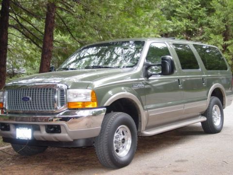1986 Ford Bronco - This Ford Excursion SUV is parked outdoors, surrounded by trees. The vehicle has a two-tone paint scheme.