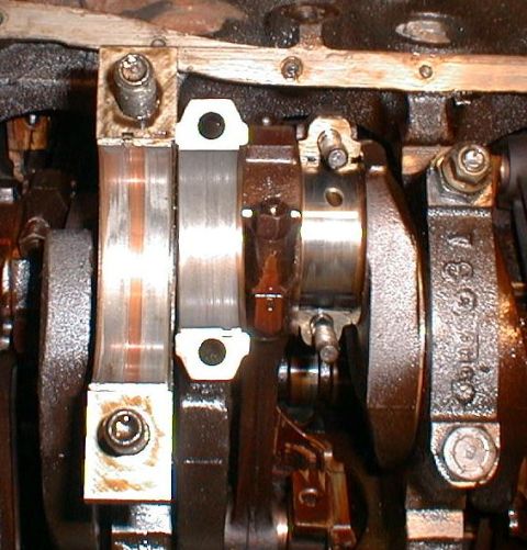1990 Ford Bronco - Close-up view of an engine's crankshaft and bearing assembly, showing wear and oil.