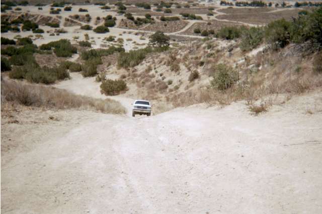 White SUV climbing a dirt trail through arid scrubland