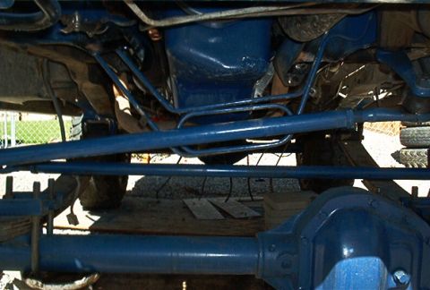 1986 Ford Bronco - The underside of a vehicle shows a blue-painted differential and suspension parts, with some tires visible in the background.