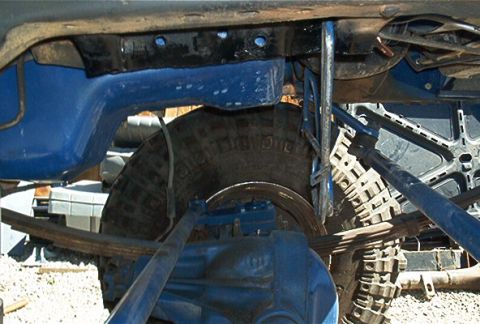 1986 Ford Bronco - Close-up view of a vehicle's undercarriage, showing suspension components and a tire.