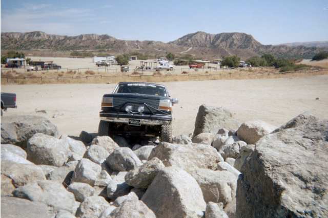 Front view of dark Ford Bronco with auxiliary lights over rocks