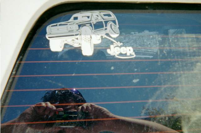 Rear window decal of an SUV with Jeep text and a self-portrait reflection