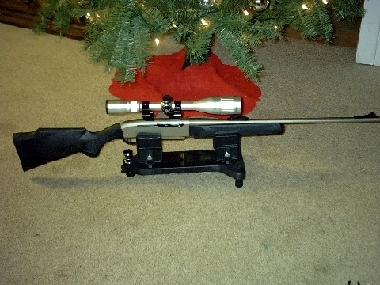 1995 Ford Bronco - A rifle with a scope is displayed on a stand, positioned beneath a decorated Christmas tree.