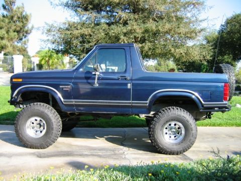 1985 Ford Bronco - This lifted 1985 Ford Bronco is shown in a side profile, its iconic body style and a rear-mounted spare tire.