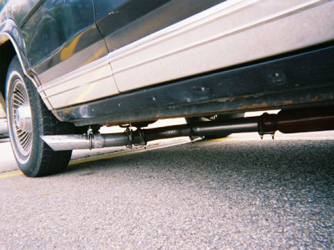 1990 Ford Crown Victoria LTD - Close-up view of the exhaust system and lower body of a vehicle, with a watermark from Supermotors.net visible.