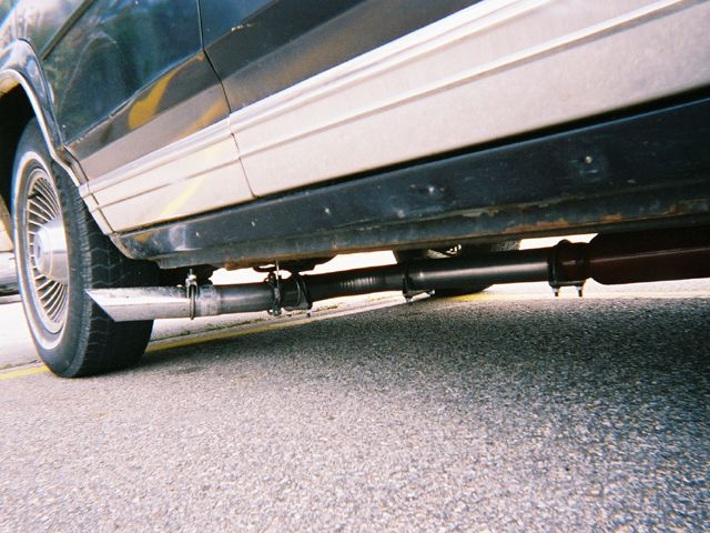 Side view of a car's exhaust system and lower body panel