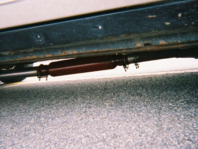 Underside view of a vehicle's exhaust system, showing a muffler or resonator
