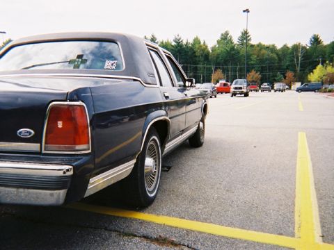 1990 Ford Crown Victoria LTD - A dark blue 1990 Ford Crown Victoria is parked in a lot with other vehicles visible in the background.