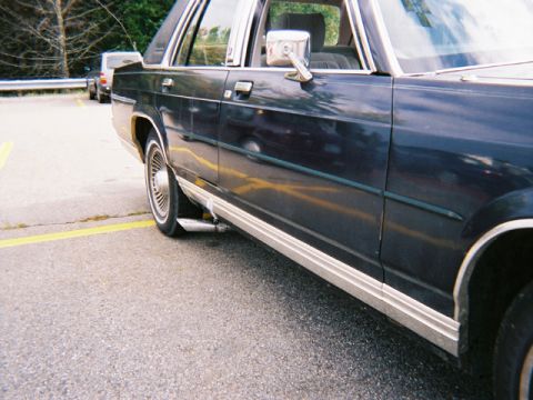 1990 Ford Crown Victoria LTD - Side view of a dark blue 1990 Ford Crown Victoria LTD sedan, chrome trim and whitewall tires.