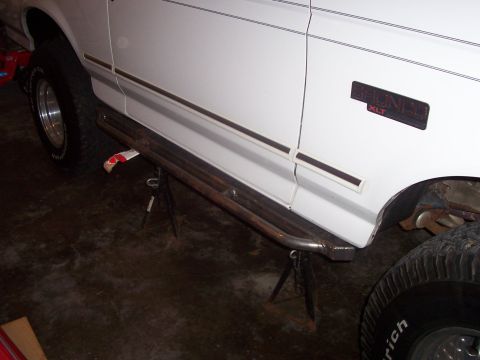 1994 Ford Bronco - A white 1994 Ford Bronco XLT is shown from the side, with custom side steps installed and the vehicle supported by jack stands.