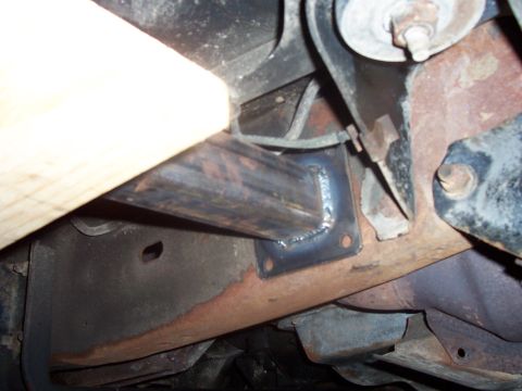 1994 Ford Bronco - Custom slider bracket welded to frame rail, showing rust and a piece of wood.