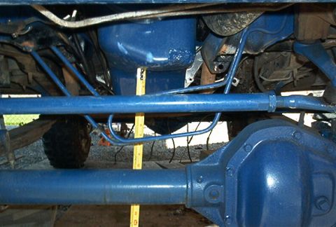 1986 Ford Bronco - The underside of a vehicle shows blue painted parts and a measuring tape, with a watermark for Supermotors.net.