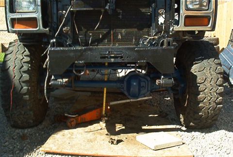 1986 Ford Bronco - Front view of a 1986 Ford Bronco's suspension and axle, large off-road tires and a custom bumper.